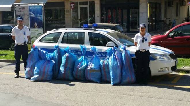 Due agenti della Polizia Municipale con i dieci sacchi di merce frutto dell'operazione contro il commercio abusivo