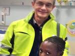 In foto la bambina senegalese al reparto di pediatria di Ravenna insieme ad un volontario Cosmohelp